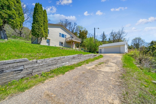 view of side of property featuring an outbuilding, a detached garage, a wooden deck, and a lawn