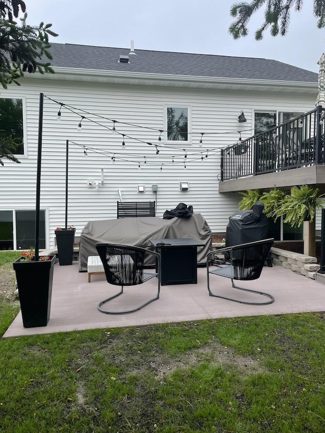 back of house featuring a patio, a lawn, and roof with shingles