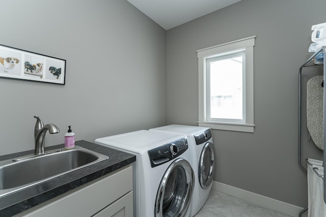 laundry area featuring cabinet space, washing machine and dryer, baseboards, and a sink