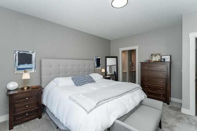 bedroom featuring light carpet, ensuite bathroom, and baseboards