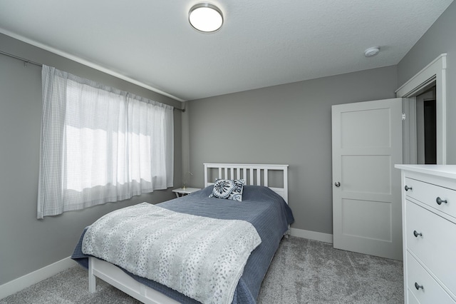 carpeted bedroom featuring baseboards and a textured ceiling