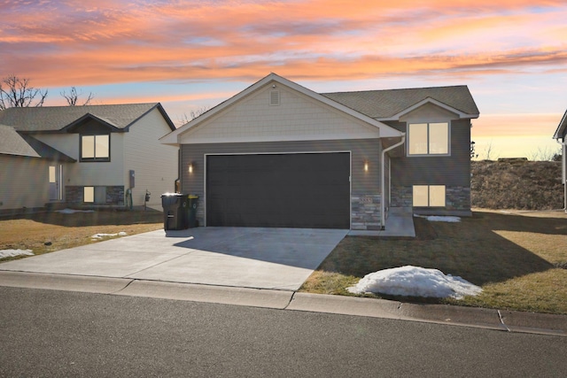 view of front of home featuring driveway, stone siding, a lawn, and an attached garage