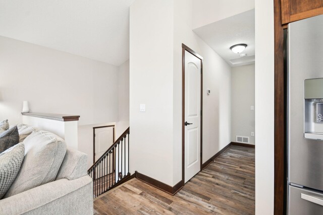 hall with baseboards, visible vents, dark wood-style flooring, and an upstairs landing