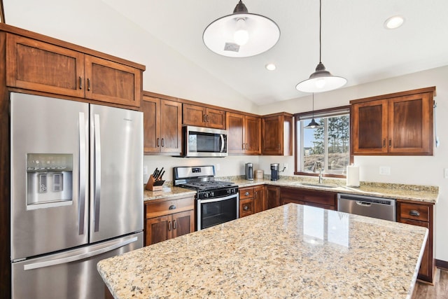 kitchen featuring a kitchen island, appliances with stainless steel finishes, hanging light fixtures, vaulted ceiling, and a sink