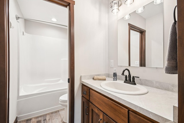 bathroom featuring toilet, shower / tub combination, wood finished floors, and vanity