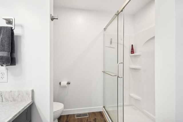 bathroom featuring vanity, a stall shower, wood finished floors, and toilet