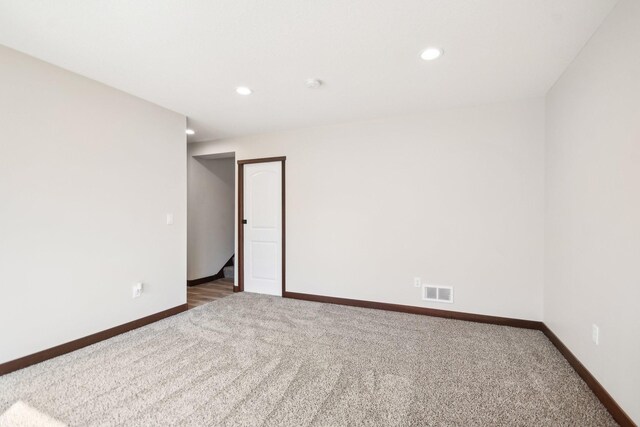 carpeted empty room with visible vents, baseboards, and recessed lighting