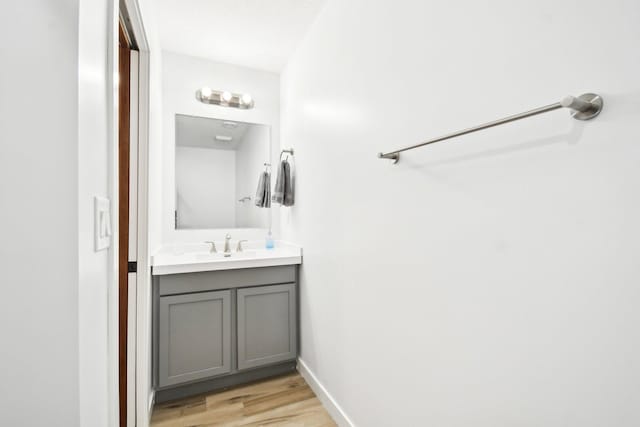 bathroom with baseboards, wood finished floors, and vanity