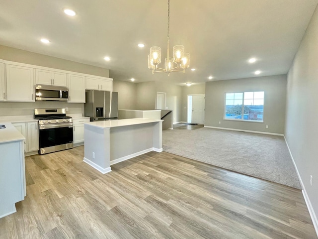 kitchen with pendant lighting, light countertops, appliances with stainless steel finishes, open floor plan, and white cabinetry