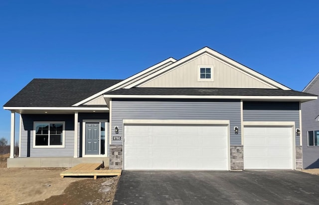 view of front facade featuring a garage, stone siding, and aphalt driveway