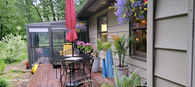 wooden deck with a sunroom and outdoor dining area