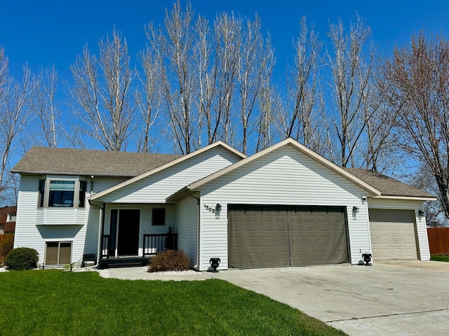 view of front of property with an attached garage, concrete driveway, a front yard, and roof with shingles