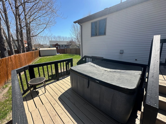 wooden deck featuring a hot tub, a shed, and an outdoor structure