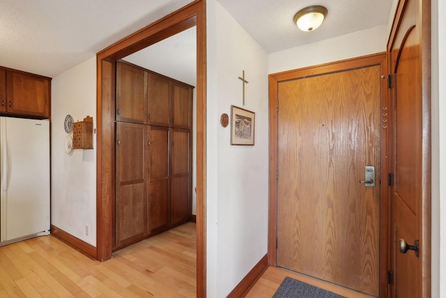 doorway with a textured ceiling and light wood-type flooring