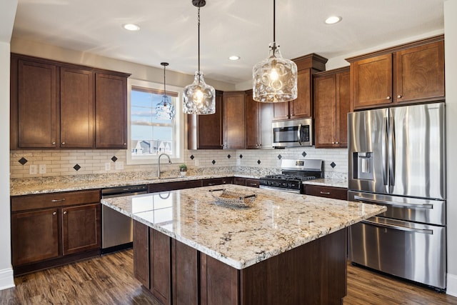 kitchen with stainless steel appliances, dark wood finished floors, a sink, and a kitchen island