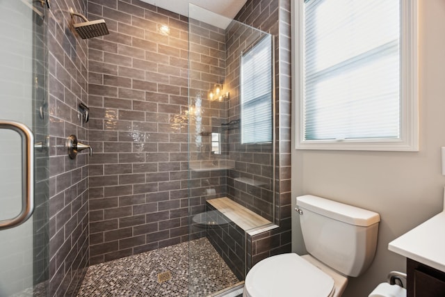 bathroom with toilet, a tile shower, and vanity