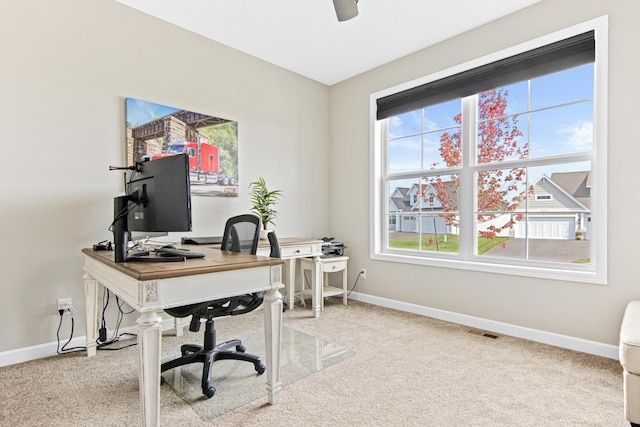 carpeted office space with ceiling fan, a healthy amount of sunlight, visible vents, and baseboards