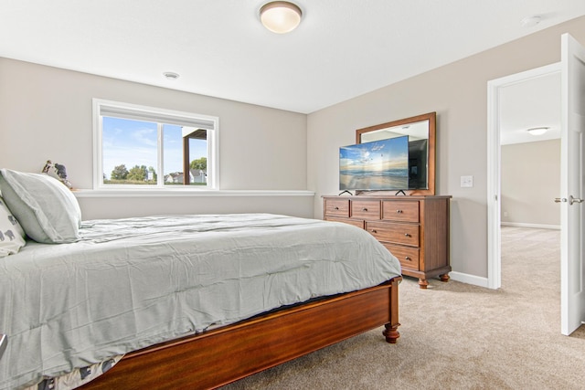 bedroom with light colored carpet and baseboards