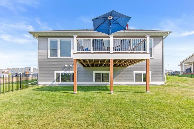 rear view of house with a deck, a lawn, and fence