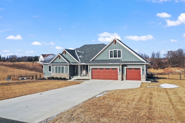 craftsman-style house with stone siding, board and batten siding, a front yard, and fence