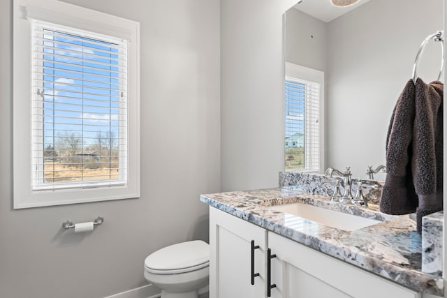 bathroom featuring toilet, baseboards, and vanity