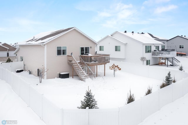 snow covered back of property with central AC unit and a wooden deck