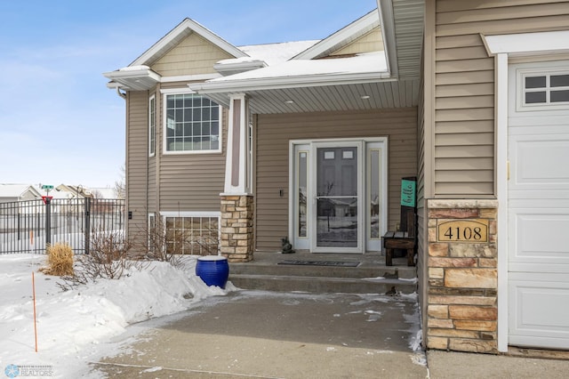 snow covered property entrance with a garage