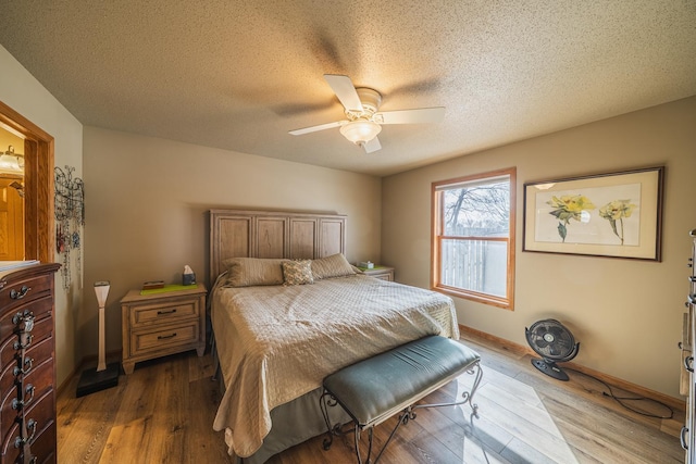 bedroom with a textured ceiling, wood finished floors, a ceiling fan, and baseboards