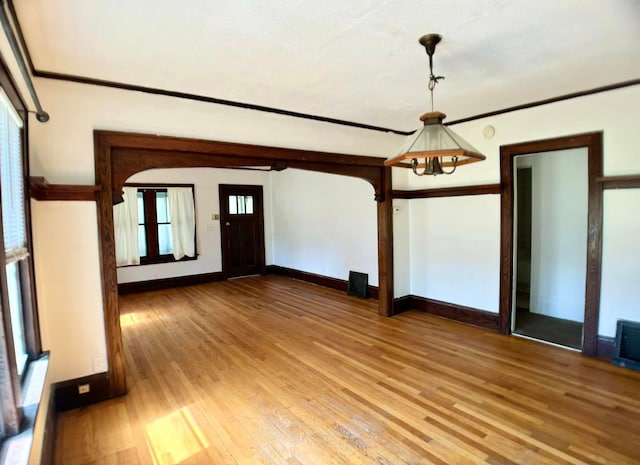 empty room with crown molding, a notable chandelier, and hardwood / wood-style flooring