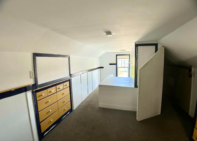 additional living space featuring vaulted ceiling and dark colored carpet