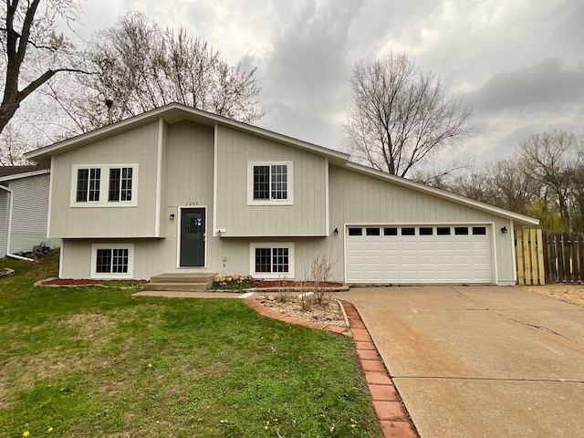 split foyer home featuring fence, a garage, driveway, and a front yard