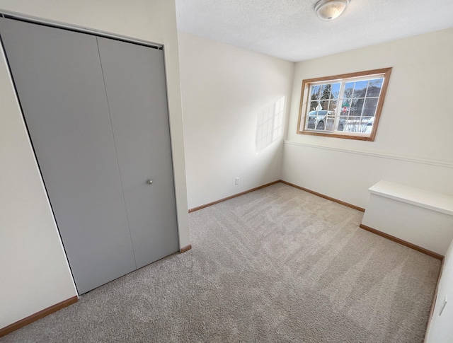 unfurnished bedroom with baseboards, a textured ceiling, carpet, and a closet