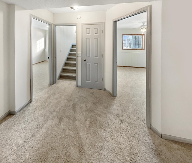 empty room with baseboards, light carpet, and stairway