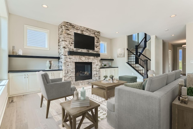 living room with a stone fireplace, a healthy amount of sunlight, and light hardwood / wood-style flooring