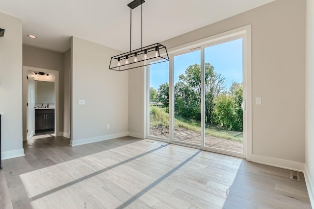 unfurnished dining area featuring hardwood / wood-style floors and an inviting chandelier