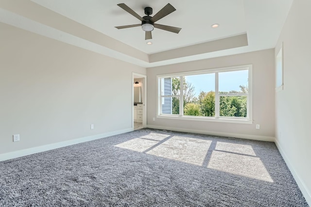 carpeted empty room with ceiling fan and a tray ceiling