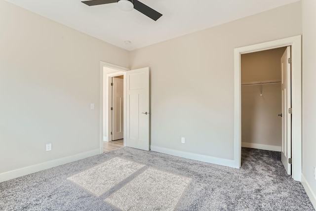 unfurnished bedroom featuring a spacious closet, light colored carpet, ceiling fan, and a closet