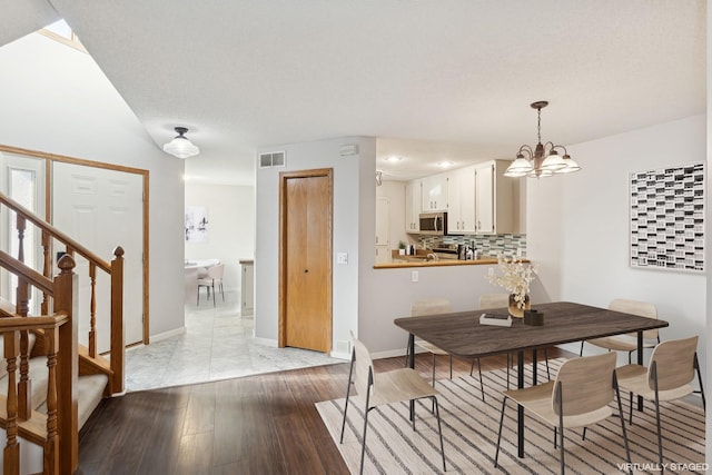 dining room with visible vents, baseboards, light wood-style flooring, stairway, and a chandelier