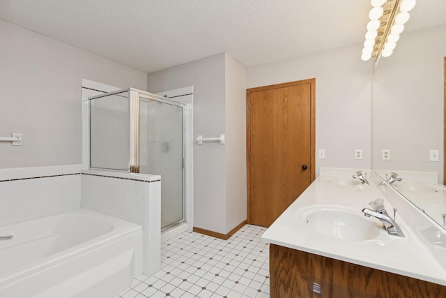 bathroom with a textured ceiling, a stall shower, and a sink