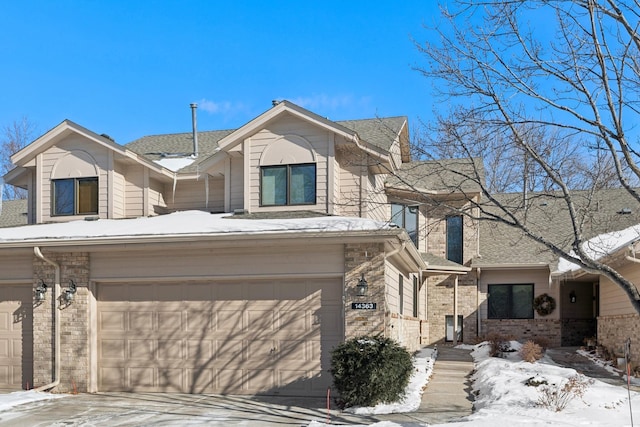 view of front facade with a garage, brick siding, driveway, and roof with shingles