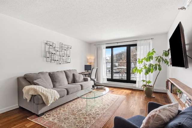 living room with a textured ceiling, baseboards, and wood-type flooring