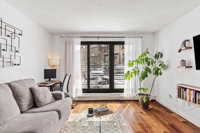 living room featuring baseboards, a textured ceiling, and wood finished floors