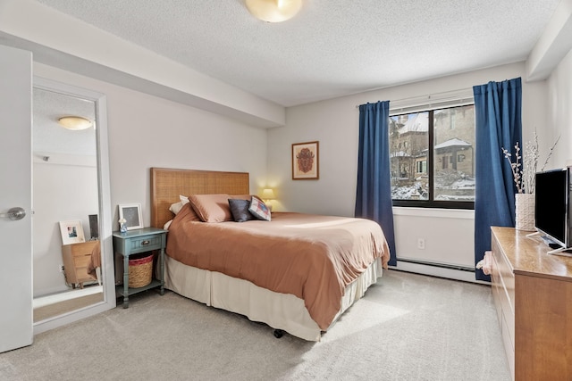 bedroom with light carpet, baseboard heating, and a textured ceiling