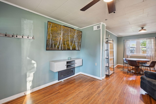 living room featuring light wood-type flooring, crown molding, and ceiling fan