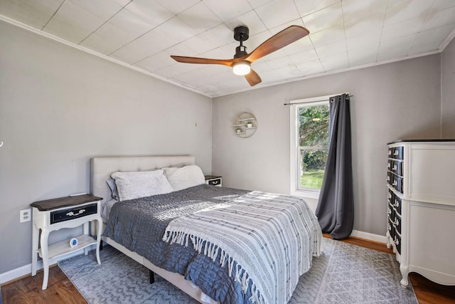 bedroom with ceiling fan, ornamental molding, and wood-type flooring