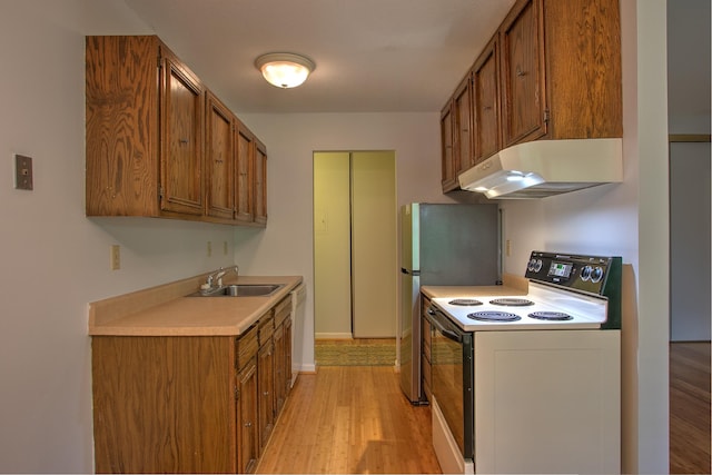 kitchen featuring under cabinet range hood, a sink, light countertops, brown cabinets, and electric range oven