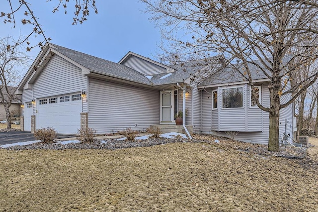 single story home with a garage, driveway, a front yard, and roof with shingles