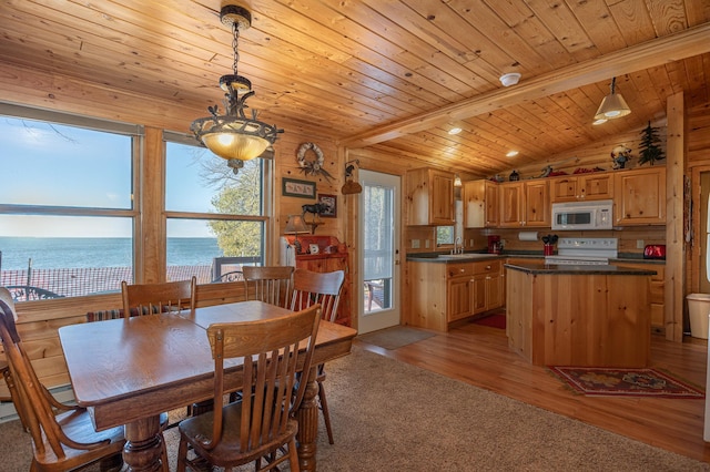 dining room with light hardwood / wood-style flooring, vaulted ceiling with beams, sink, a water view, and wooden ceiling