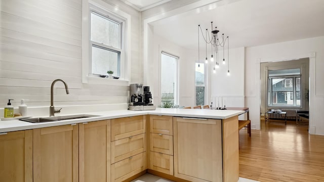 kitchen featuring a sink, a peninsula, light brown cabinets, and light countertops