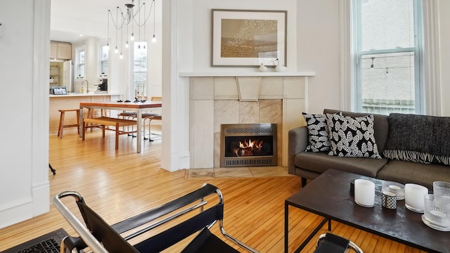 living area with a wealth of natural light, light wood-style flooring, and a tiled fireplace